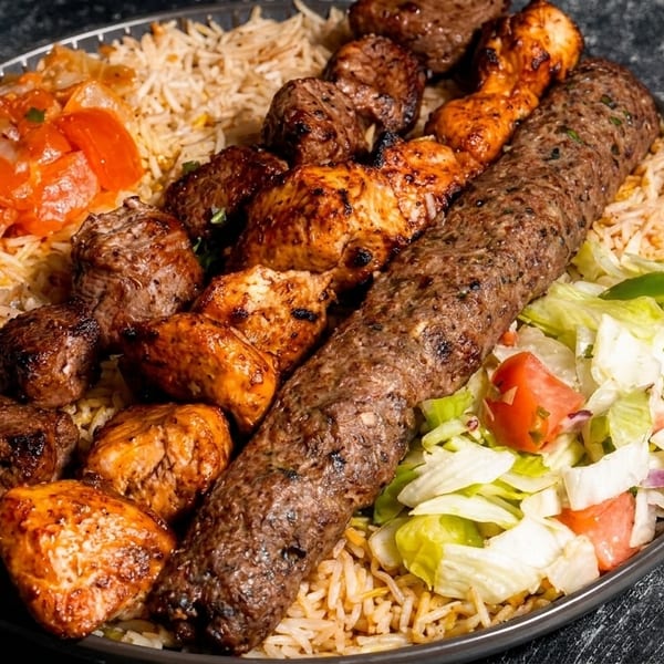 A platter of rice, beef and chicken kebabs, a long kofta, and a side salad.