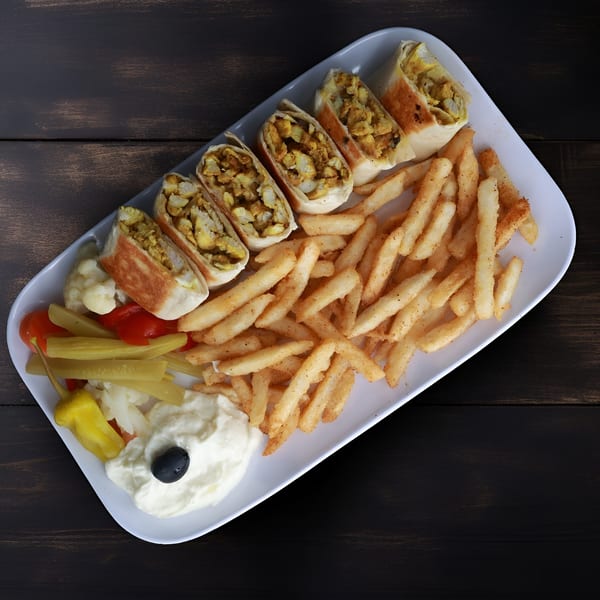 Chicken shawarma wraps, french fries, pickles, and garlic sauce with an olive on a white plate.